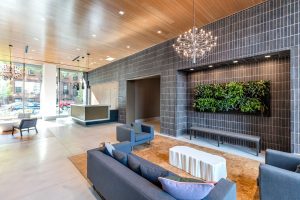 bright chic lobby with dark paneling, greenery, and chandelier