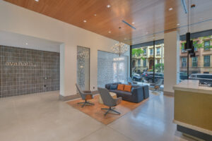 Interior Lobby, white walls, concrete floor, contemporary front desk, 2 love seats with 2 lounge chairs across from both.