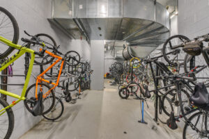 Interior bike rack, wall mounts, large industrial heat vent above racks, concrete floor.