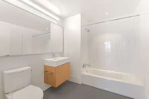 Interior unit bathroom, light brown cabinets, large vanity mirror, bathtub/shower.