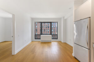 Interior Unit Living Room, wood floors, white walls, stainless steel appliances in kitchen.