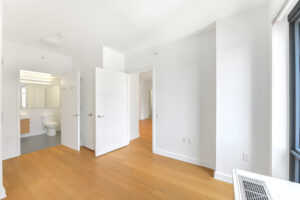 Interior Unit Bedroom, attached bathroom, wood floors, white walls,.